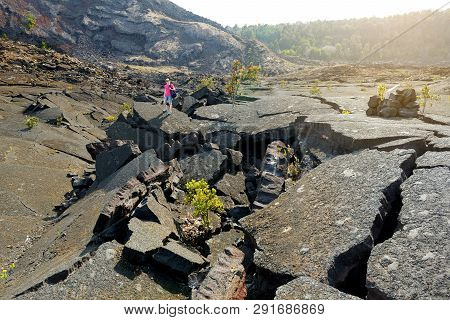 Young Female Tourist Exploring Surface Of The Kilauea Iki Volcano Crater With Crumbling Lava Rock In