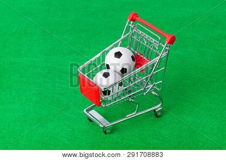 Soccer balls in shopping cart on green foorbal field