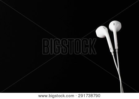 White Earbuds Or Earphones On Black Background. Copy Paste Space.