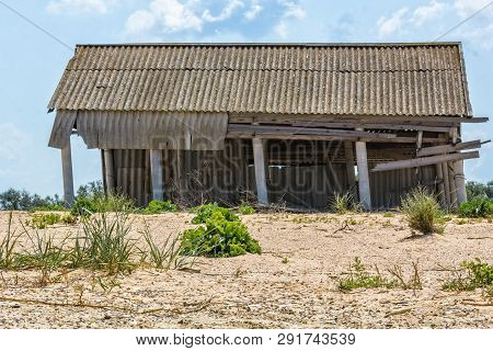 Ruined Barn On An Abandoned Farm Against A Blue Sky With Clouds, Close-up