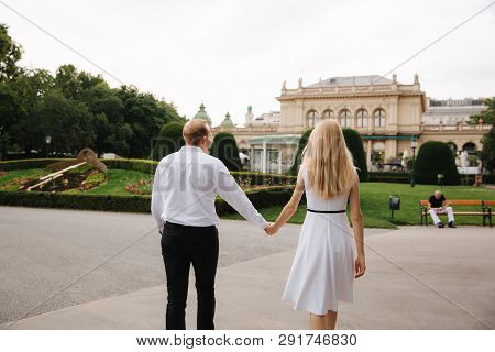 Beautiful Cuple Stand On The Stairs And Hug Each Other. Man And Woman Walking In The Park. Love Stor