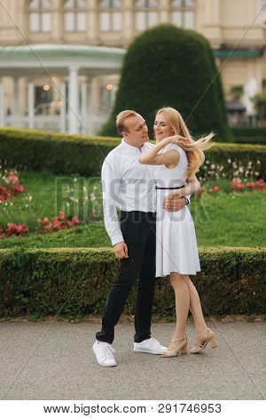 Beautiful Cuple Stand On The Stairs And Hug Each Other. Man And Woman Walking In The Park. Love Stor