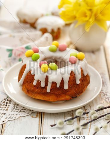 Easter Yeast Cake (babka) Covered With Icing And Decorated With Marzipan Eggs On A White Plate On A 