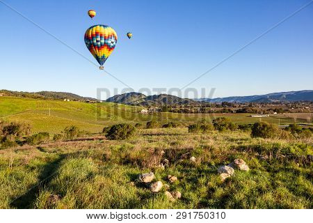 Hot Air Balloons Over Napa Valley Vineyards At Sunrise With Blue Sky And Copy Space.
