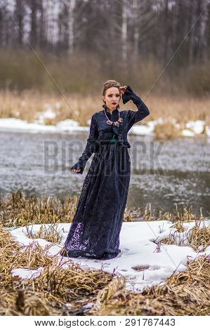 Gentle And Vulnerable Caucasian Brunette Female In Art Dress With Necklace And Crown Posing Against 