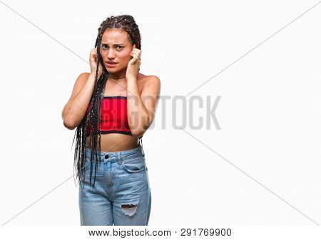 Young braided hair african american with pigmentation blemish birth mark over isolated background covering ears with fingers with annoyed expression for the noise of loud music. Deaf concept.