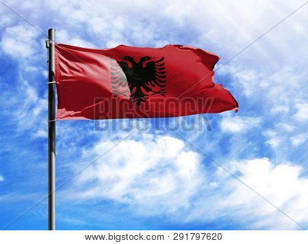 National Flag Of Albania On A Flagpole In Front Of Blue Sky.