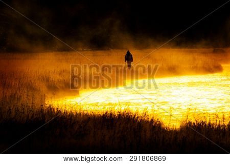 Silhouette of Fishing Flyfishing rod reel in river with golden sunlight