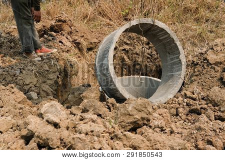 Worker Burying Pipe On Ground For Making Septic Tank At Construction Site