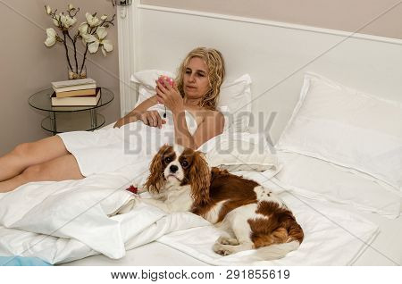 Woman And Doggy Relaxing On A Bed