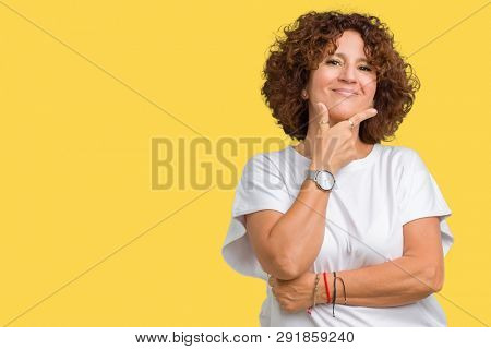 Beautiful middle ager senior woman wearing white t-shirt over isolated background looking confident at the camera with smile with crossed arms and hand raised on chin. Thinking positive.