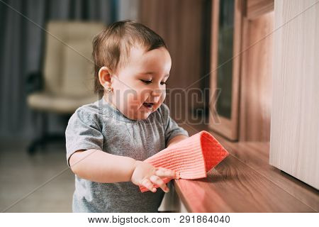 A Little Girl With A Rag Wiping The Dust From The Cabinet