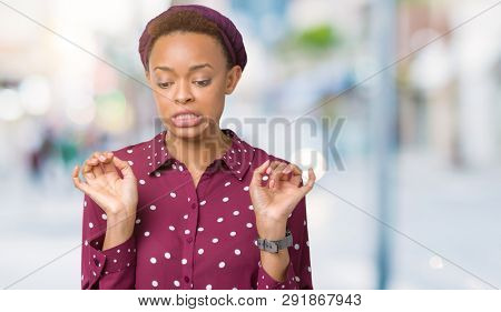 Beautiful young african american woman wearing head scarf over isolated background disgusted expression, displeased and fearful doing disgust face because aversion reaction. With hands raised.