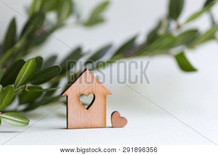 Closeup Wooden House With Hole In Form Of Heart With Green Buxus Branch On Light Background With Cop