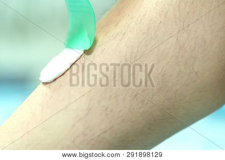 Woman Epilating Leg With Depilation Cream And Spatula. Scrubs Hair Removal Cream