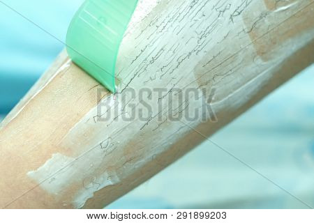 Woman Epilating Leg With Depilation Cream And Spatula. Scrubs Hair Removal Cream