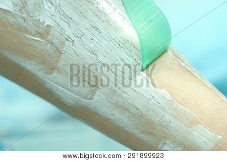 Woman Epilating Leg With Depilation Cream And Spatula. Scrubs Hair Removal Cream