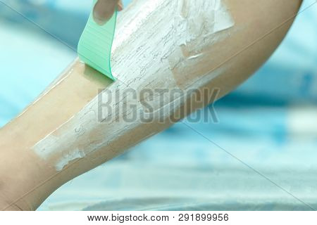 Woman Epilating Leg With Depilation Cream And Spatula. Scrubs Hair Removal Cream