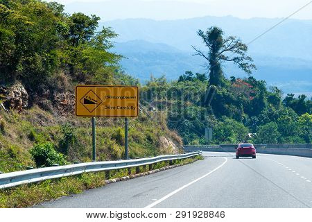 Caution Long Descent Road Sign On Highway Through Mountains