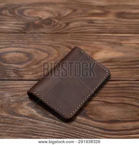 Brown Two-pocket Closed Leather Handmade Cardholder Lies On Wooden Background. Soft Focus On Backgro