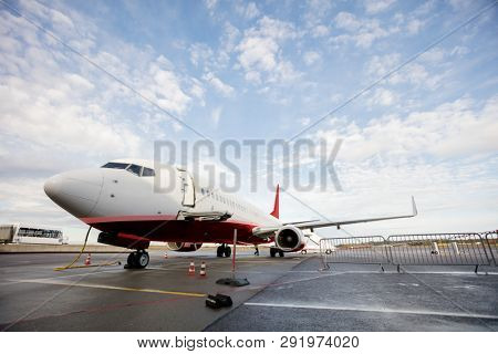 Commercial Airplane On Wet Runway Against Cloudy Sky
