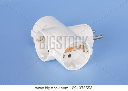 White Splitter For 220 Volt Electricity Grid On A Blue Background. Splitter For Simultaneous Switchi
