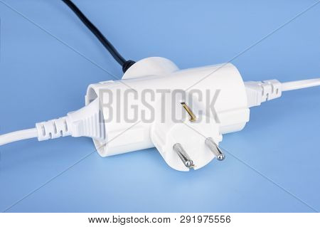 Tree Plugs Socketed Into White Electric Splitter On A Blue Background. Splitter For Simultaneous Swi