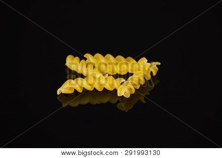 Group Of Four Whole Raw Italitan Yellow Pasta Torti Isolated On Black Glass