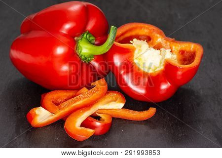 Group Of One Whole One Half Four Slices Of Bulgarian Red Bell Pepper On Grey Stone