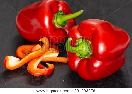 Group Of Two Whole Four Slices Of Bulgarian Red Bell Pepper On Grey Stone