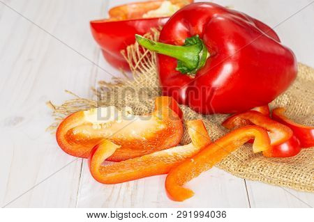Group Of One Whole One Half Four Slices Of Bulgarian Red Bell Pepper On Jute Cloth On White Wood