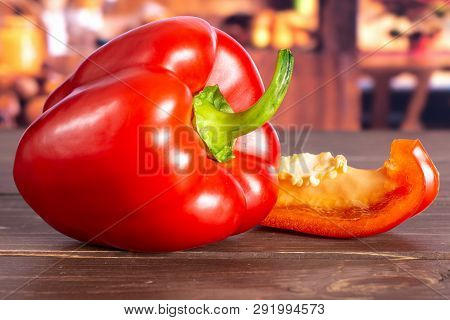 Group Of One Whole One Slice Of Bulgarian Red Bell Pepper With Rustic Wood Kitchen In Background