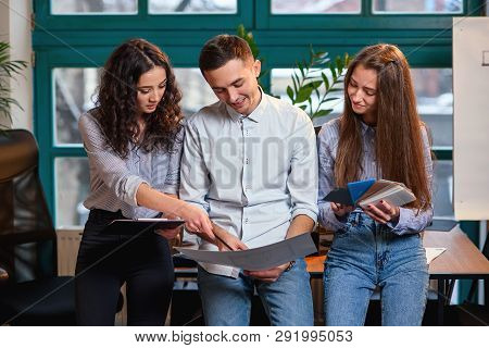 Successful Team Of Young Caucasian Engineer Standing Near Wooden Table And Talking About New Project