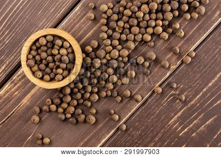 Lot Of Whole Dry Brown Allspice Berries With Wooden Bowl Flatlay On Brown Wood