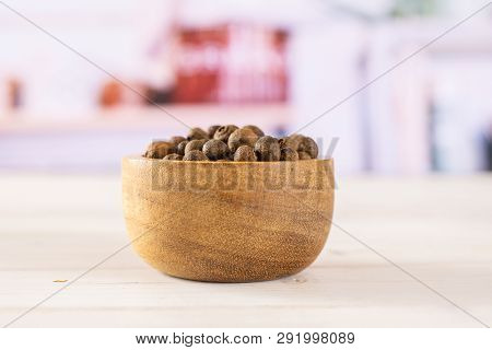 Lot Of Whole Dry Brown Allspice Berries With Wooden Bowl With Grey Kitchen In Background