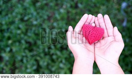 Red Knitted Heart In Hands. Concept Of Love, Mercy, Sympathy Close Up. Moms Day. Mothers Day Holiday