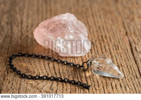 The Pendulum On A Chain With A Natural Crystal On A Background Of Wood Texture
