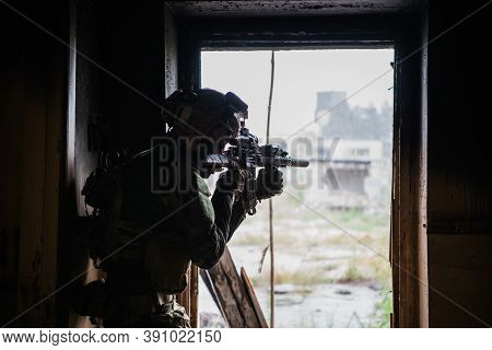 Soldier In Full Us Marsoc Armed With Assault Rifle Run Through The Abandoned Building. Military Clas