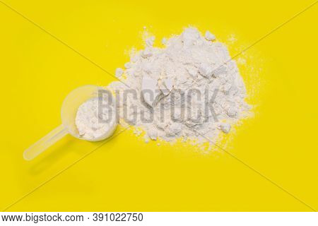 Heap Of Protein Powder With Plastic Spoon On Yellow Background