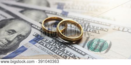 Wedding Rings On The Background Of 100 Dollars Bills. Marriage Conctract Or Prenuptial Agreement Con