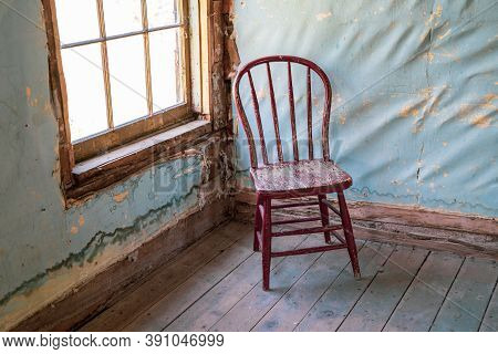 Wooden Red Chair In A Corner In An Abandoned, Decaying Home In Bannack Ghost Town In Montana