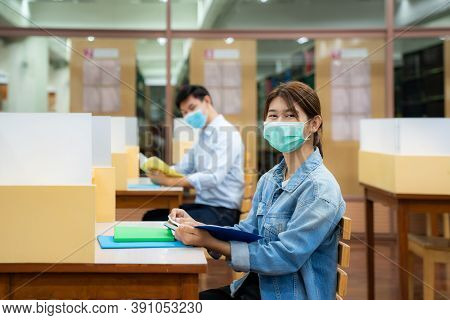 Two Asian University Students Wearing Face Mask And Sitting And Smile In Library Social Distance Fro