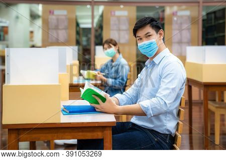 Two Asian University Students Wearing Face Mask And Sitting And Smile In Library Social Distance Fro