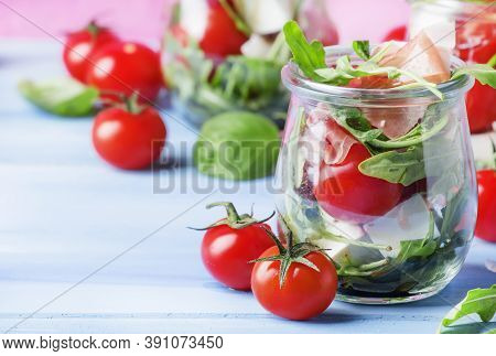 Summer Salad With Arugula, Soft Cheese, Cherry Tomatoes And Prosciutto In Glass Jars, Festive Backgr