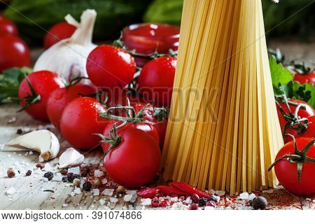 Italian Dry Pasta Spaghetti With Tomatoes And Fresh Herbs On A Dark Wooden Background, Selective Foc