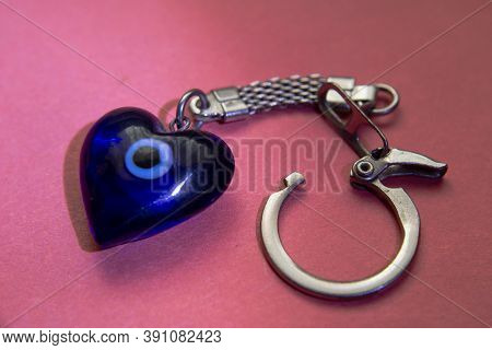 Blue Keychain On The Clasp On The Red Table.