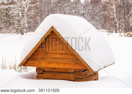 Picturesque Winter Landscape With Snow Covered Roof Of Wellspring In Cloudy Day After Snowfall. Seas