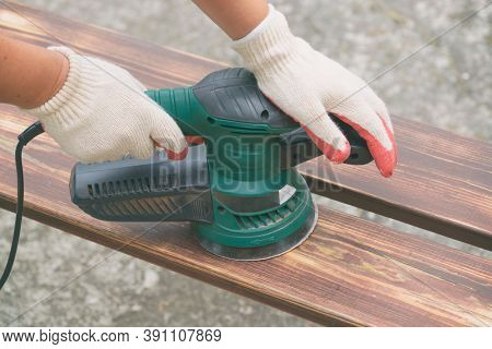 Sanding a wood with orbital sander outdoor