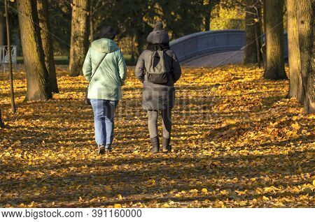 Indian Summer Two Unidentified Women Walk Through A Picturesque Sunny Park View Of Their Backs