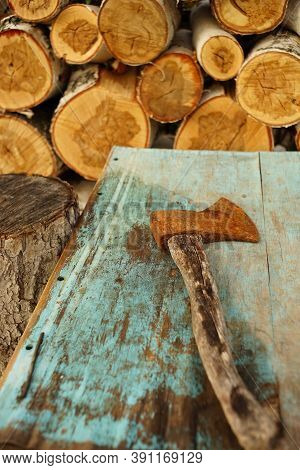 Old Rusty Ax Lies On The Blue Shabby Table Near Logs Of Birch Wo